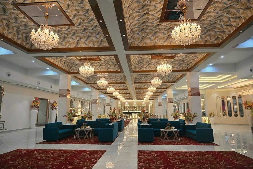 The Ambience banquet hall with crystal chandeliers, a carved ceiling and blue sofas