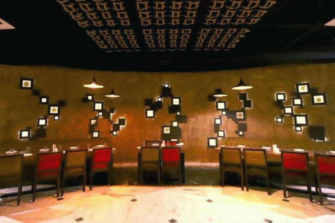 AROMA's dining room with warm lights, framed art on the wall and red chairs