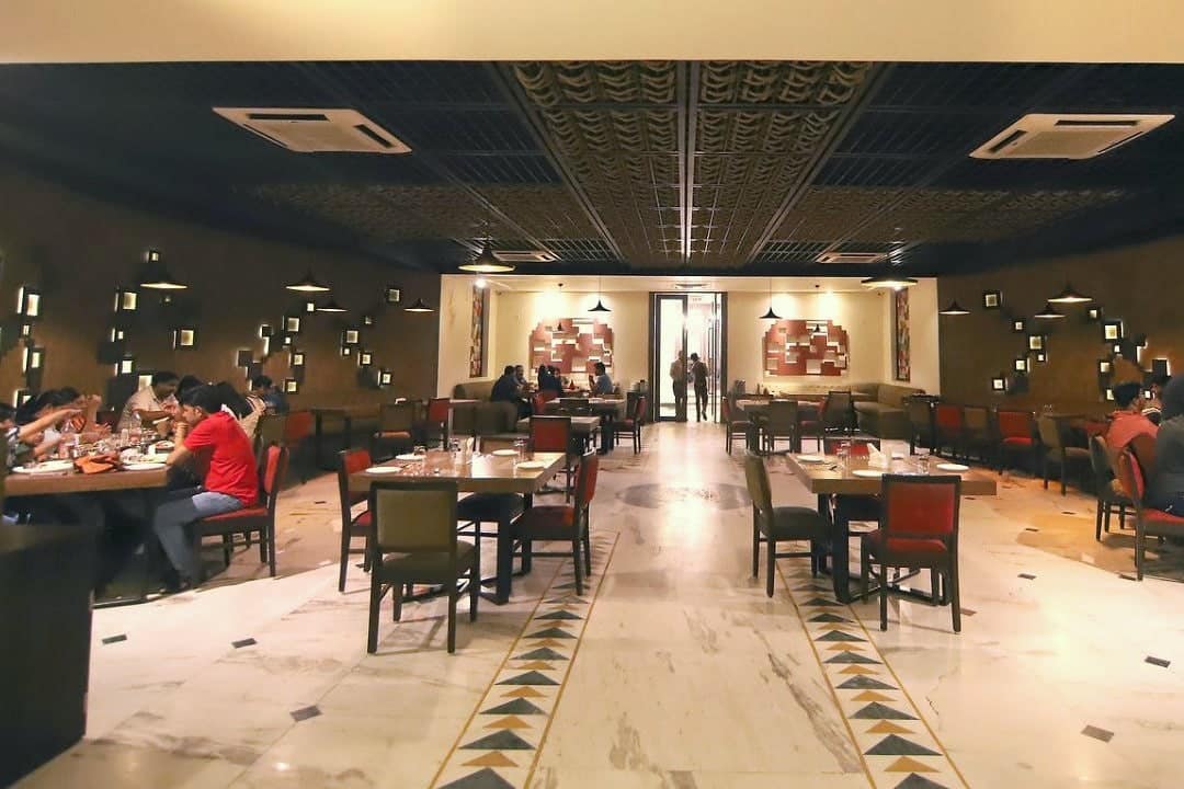 The AROMA dining room with guests at tables and an inlaid marble floor