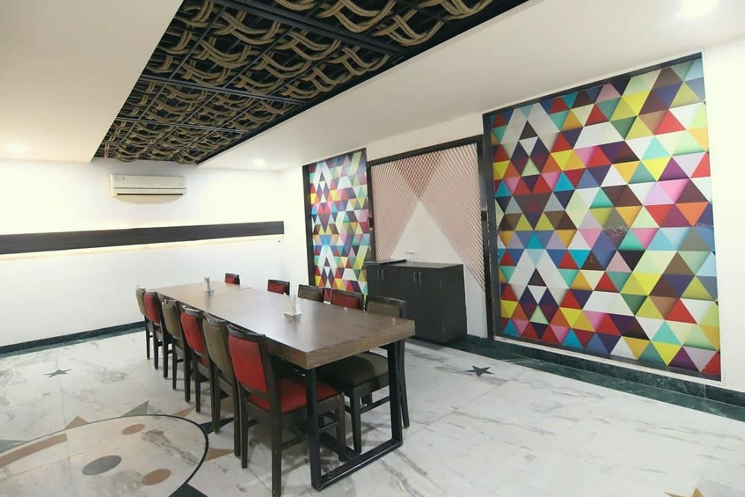 A long private dining table beside a colourful geometric wall