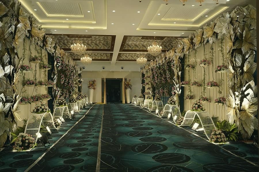 A long decorated corridor with chandeliers and floral walls leading to the stage