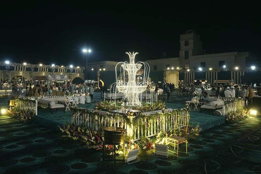 A lit fountain at the centre of a decorated lawn at night