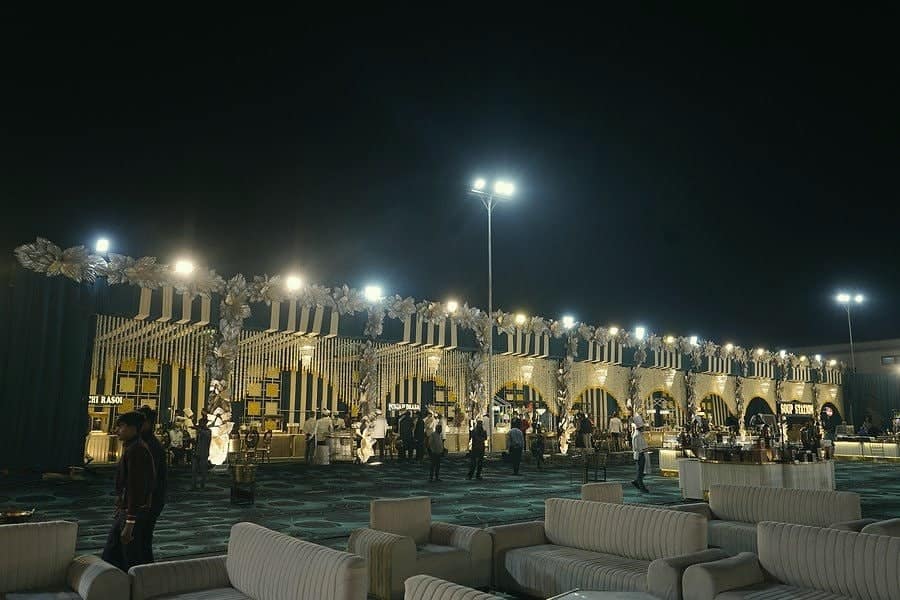 White lounge seating arranged across a lawn under festoon lights