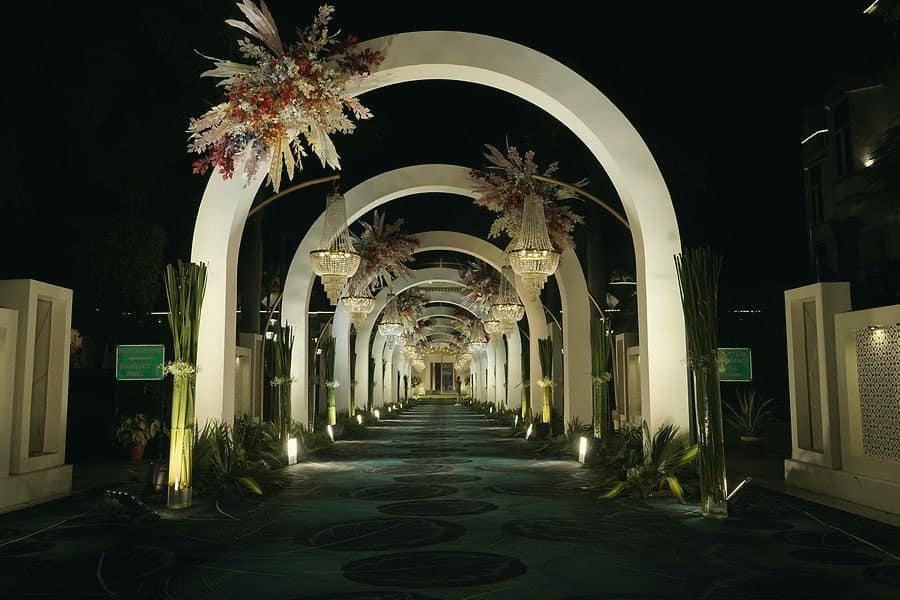 A procession of tall white arches lit up along a pathway at night