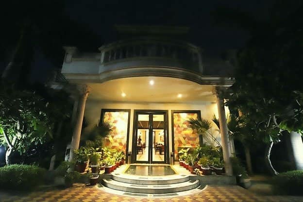 The covered entrance porch lit up at night, surrounded by plants