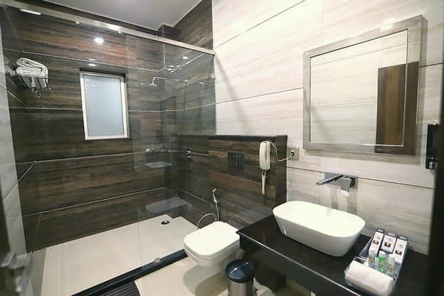 An attached bathroom with a vessel basin, mirror and glass shower