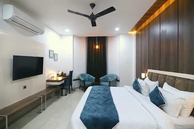 A suite with a king bed, blue cushions, armchairs and a writing desk
