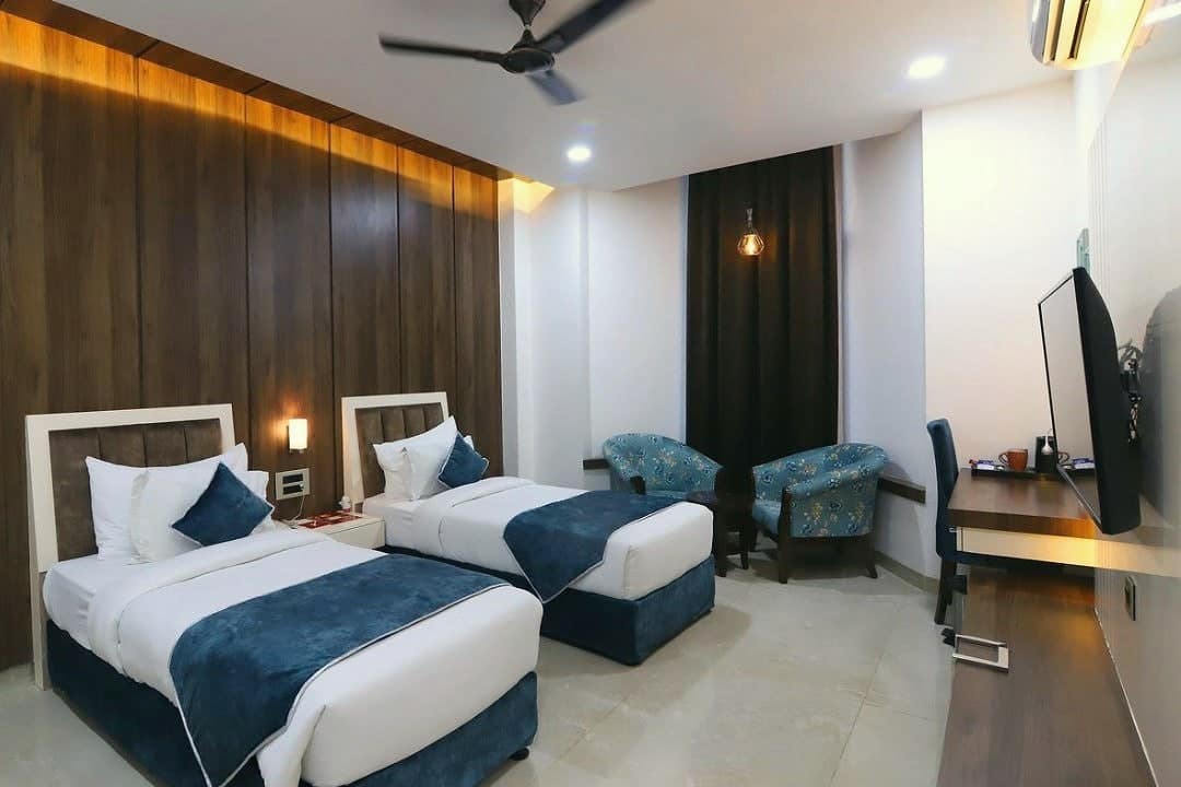A guest room with two beds dressed in white and blue, and a wooden feature wall