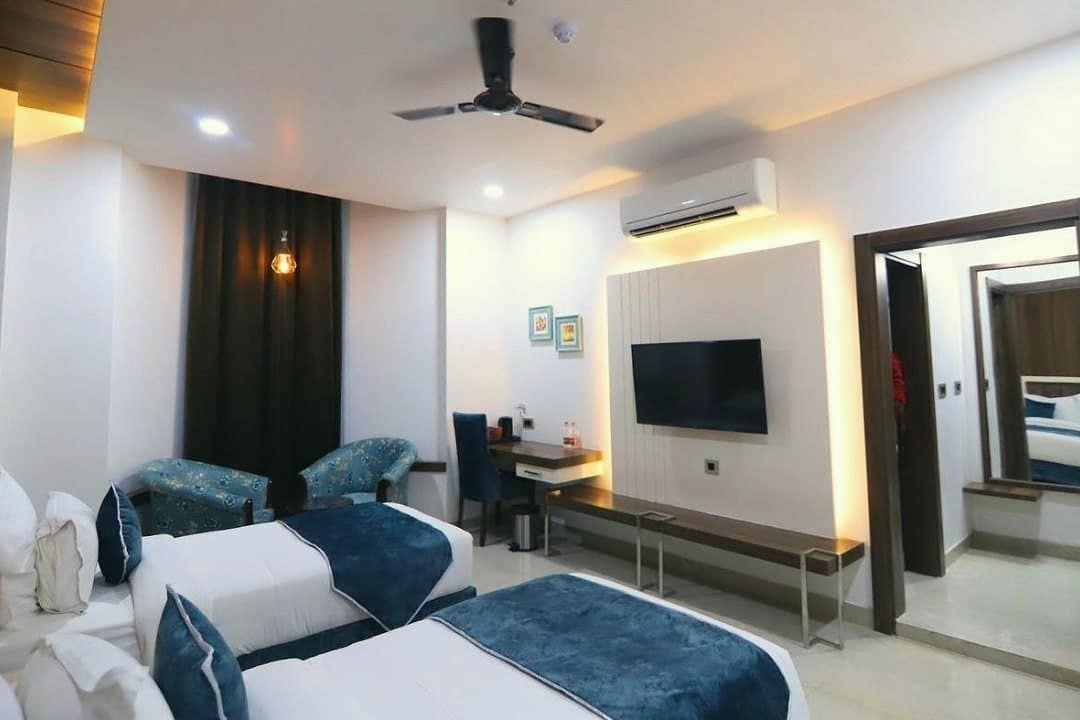 A guest room seen from the door, with beds, armchairs and a desk