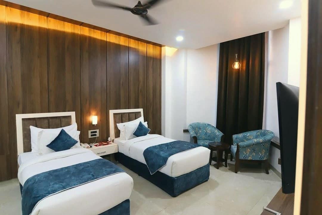 A guest room with two beds, bedside lamps and a seating corner