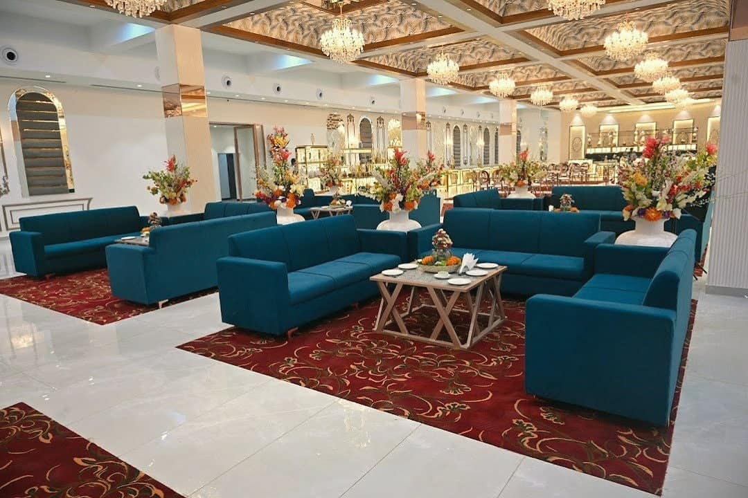 A bright lounge with teal sofas, flowers and a red patterned carpet